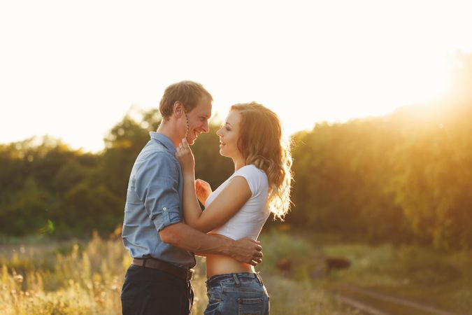 Couple kissing at sunset in green field