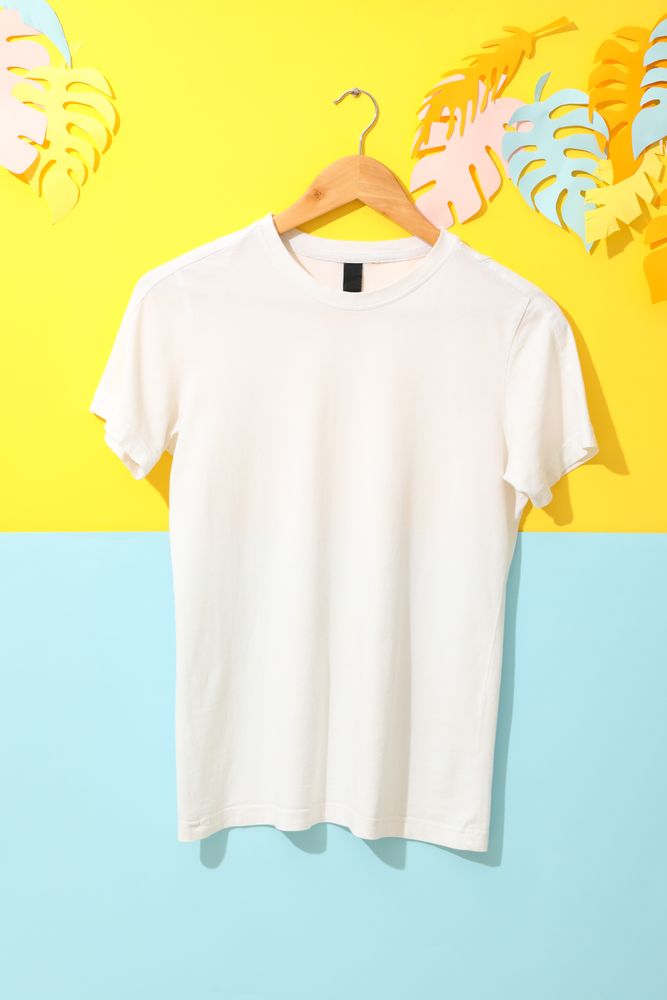 Hanger with blank plain t-shirt on two tone background, space for text