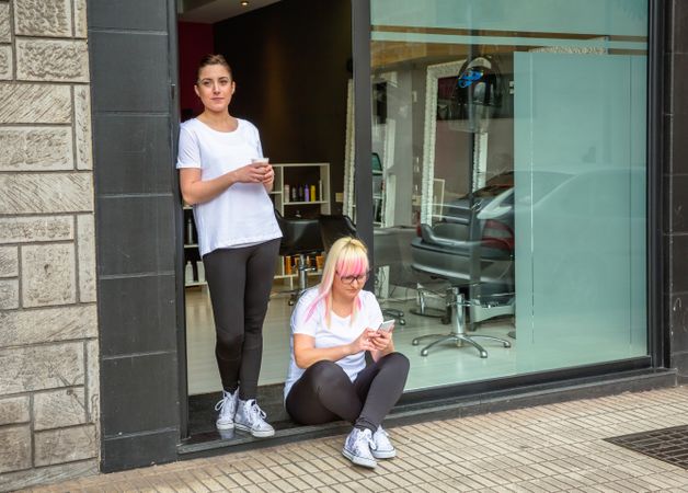 Hair stylists taking break outside door of salon