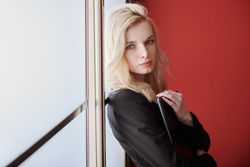 Young adult business woman standing next to the window holding phone