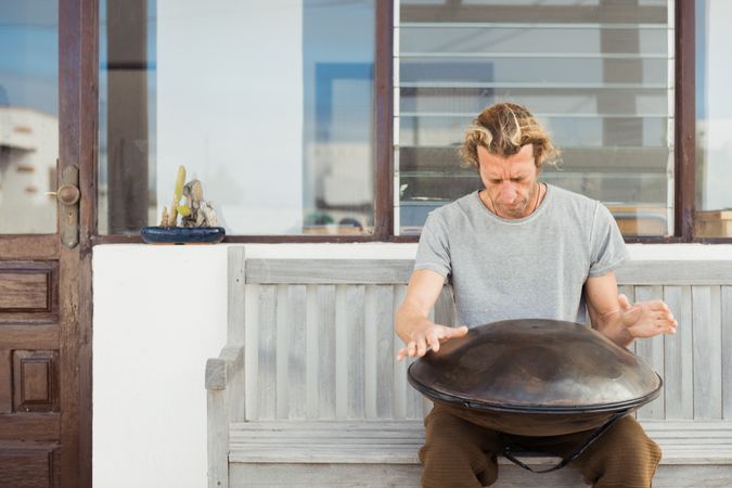 Blond man sitting on bench with big hand drum