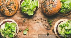 Fresh vegan burgers on seeded buns arranged on wooden board, with copy space bYvXX0