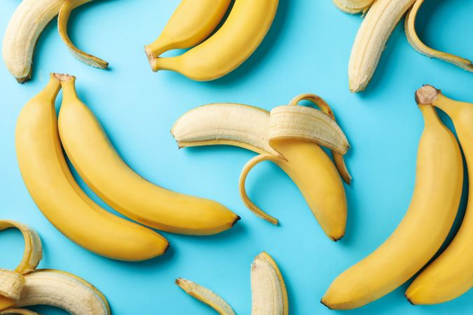 Bananas and apples on blue background, top view. Fresh fruit