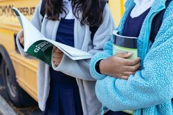 Close-up shot of two girls in school uniforms holding school books standing outdoor