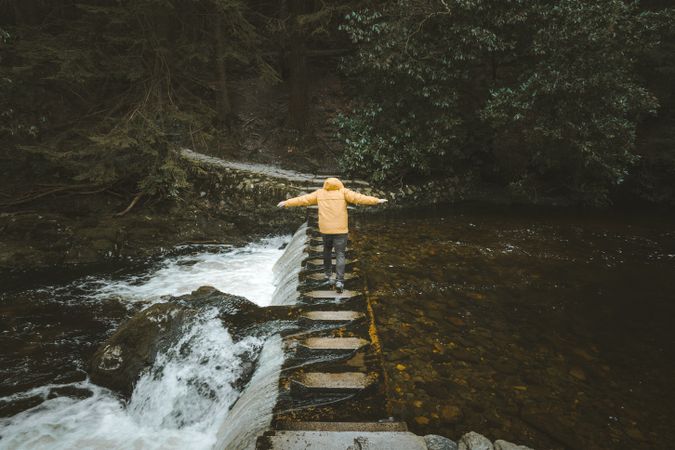 Balancing traveler crossing river on stepping stones