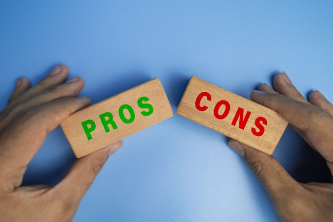 male hands holding pros and cons wooden blocks isolated on blue background