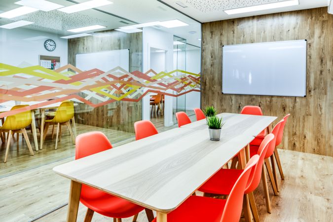 Interior of light modern office with colorful furniture against big window