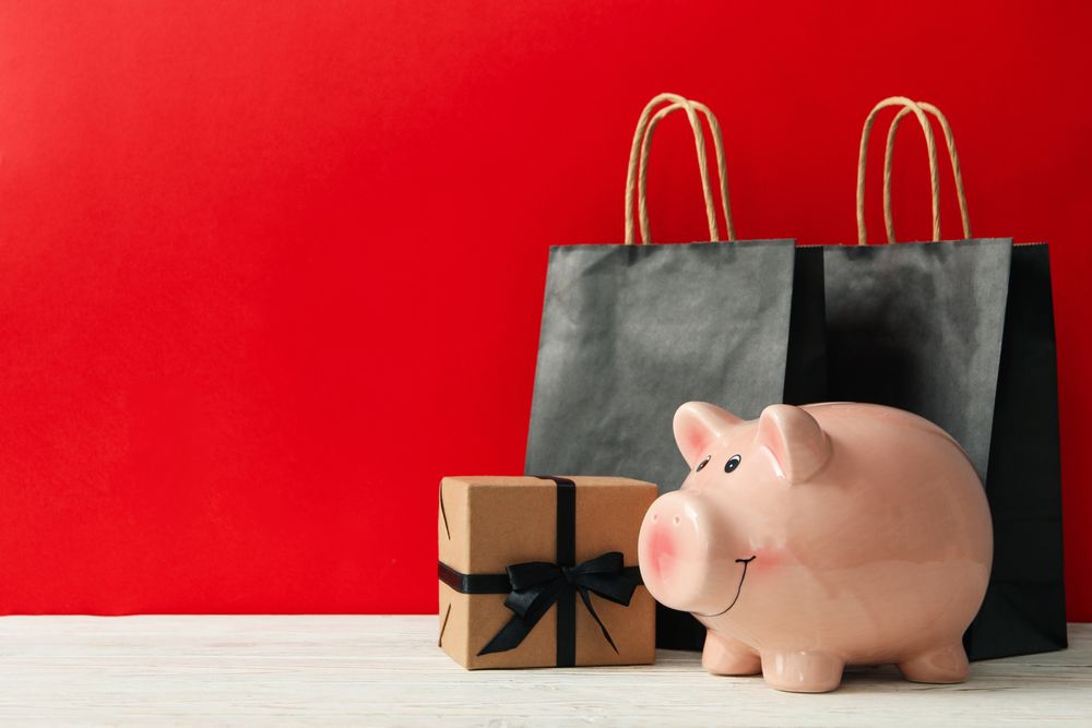 Gift box, paper bags and piggy bank against red background