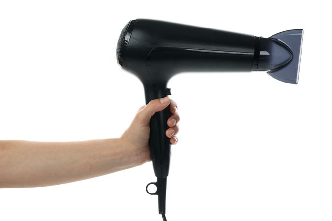 Female hand holds hair dryer, isolated on plain background