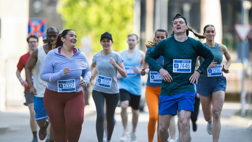 Group of Diverse People Running in a Marathon with the Cheers of their Loved Ones and Supporters in the Audience.