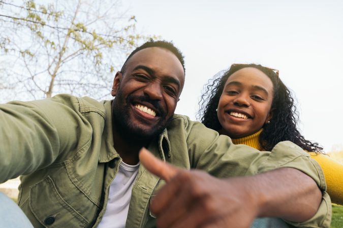 Black couple taking a selfie sitting in a park