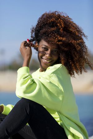Vertical portrait of happy female with curly hair in bright green shirt