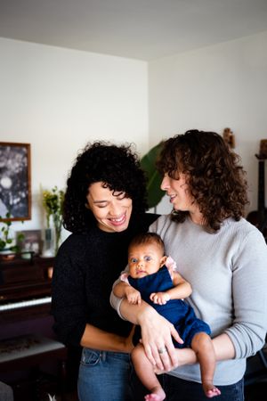 Happy couple looking down at their baby in the living room, vertical