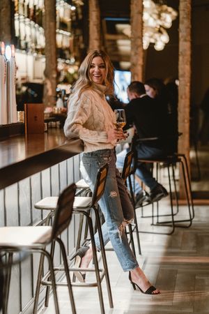 Stylish woman drinking wine in bar