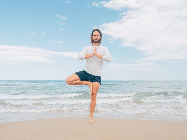 Man training yoga on beach