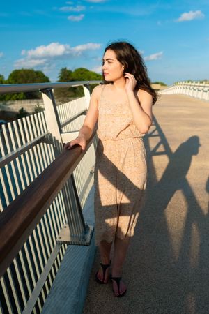 Peaceful woman in dress walking along rural bridge