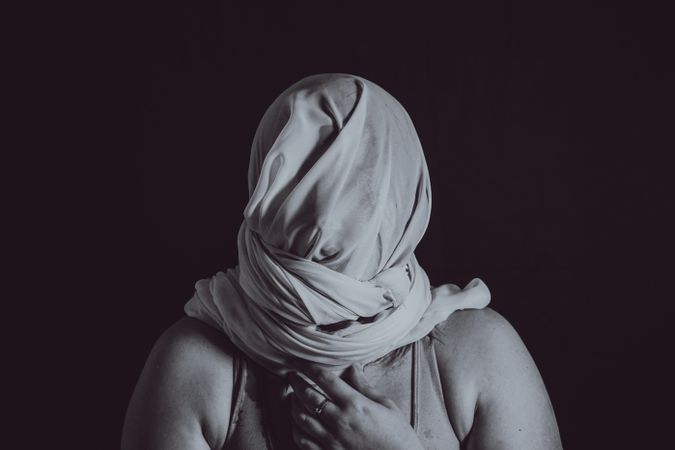 Grayscale photo of person covering their head with textile