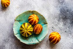 Organic mini melons in teal bowl with copy space