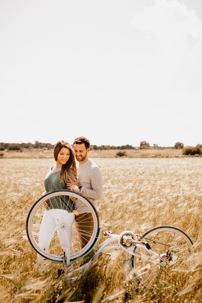 Sincere lovers posing by bicycle on rye field