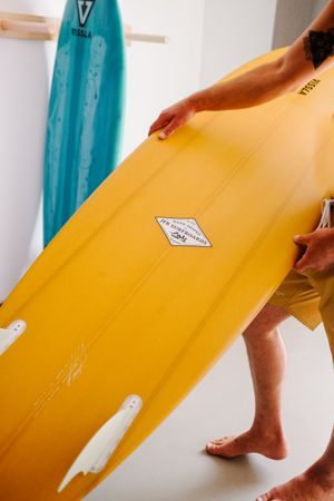 Man lifting yellow surfboard at home before heading to the beach