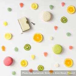 Fruit slices, gummies, and macarons and diary with lock on light background 4jXmv0