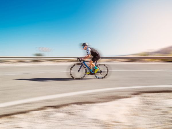 healthy man riding a bicycle on a mountain road in a sunny day