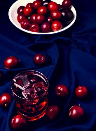 Red beverage near fresh fruits on cloth