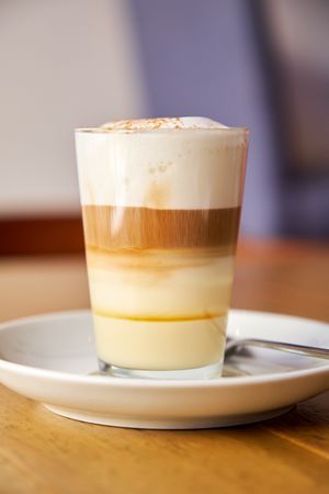 Vertical photo of a coffee with milk served in a crystal glass