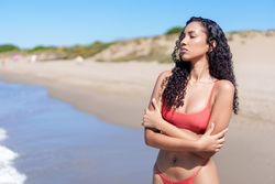 A Stunning Beach Portrait Featuring a Woman Posing Gracefully in a Bikini by the Ocean