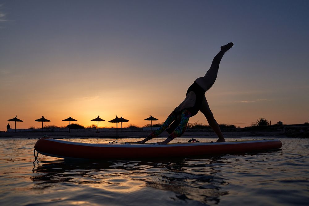 Silhouette of female athlete taking Downward Facing Dog pose on