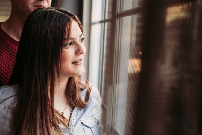 Pregnant woman with husband looking at window at home