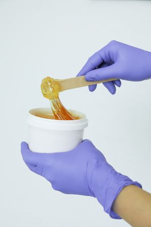 Women's hands holding liquid yellow paste for sugaring against, copy space