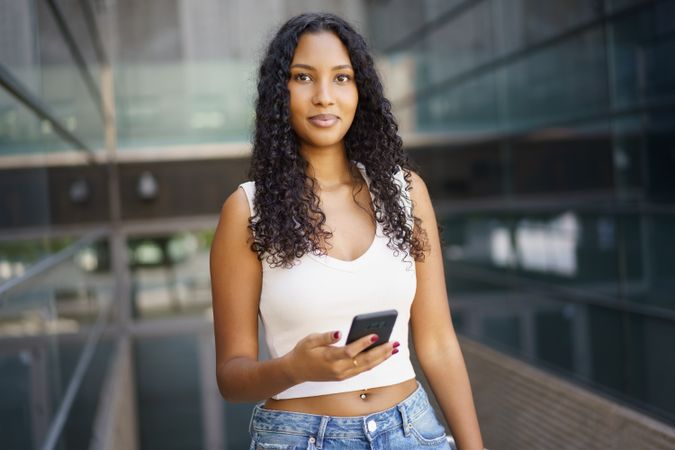 A Confident Young Woman Holding a Smartphone in a Vibrant Urban Environment, Radiating Energy