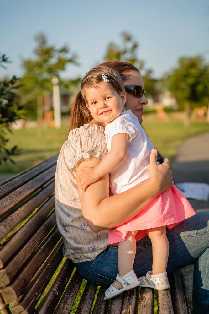 Baby girl standing on a bench hugging to woman
