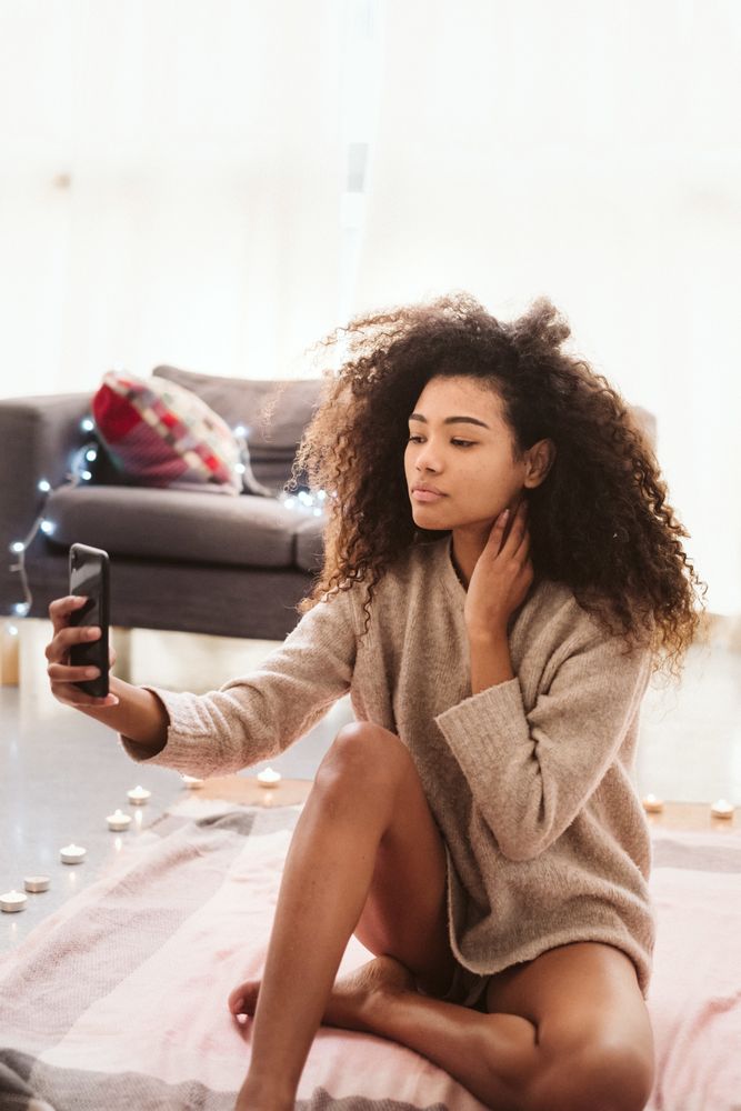 Black woman taking selfie on floor