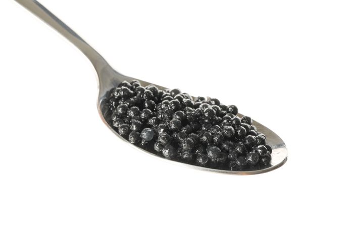 Spoon with caviar isolated on plain background