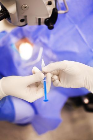Hands in latex gloves passing syringe in surgery