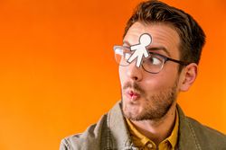 Smiling man with funny paper toy on eyeglasses