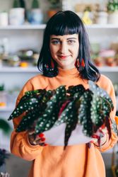 Woman holding exotic plant in a pot.