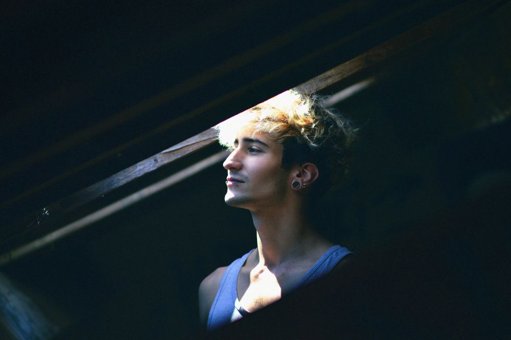 Low-light photo of man standing near open window