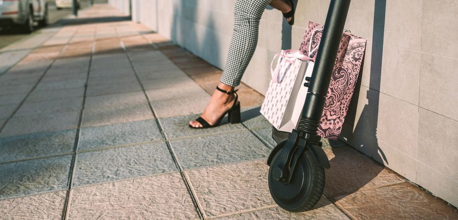 Electric scooter with shopping bags in the street and woman in background.