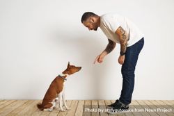 Casual, tattooed man leaning down to dog 5RoGA4