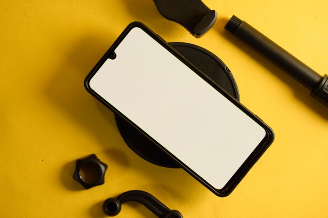 Mock up phone resting on accessories on yellow background