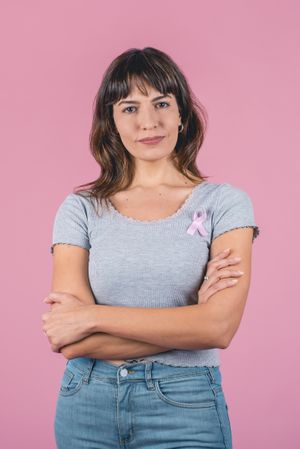 Serious woman wearing pink breast cancer awareness ribbon. Vertical shot.
