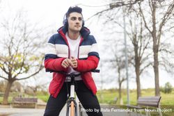 Handsome cool young man enjoying a bicycle ride and listening to music on headphones 4BaJJW