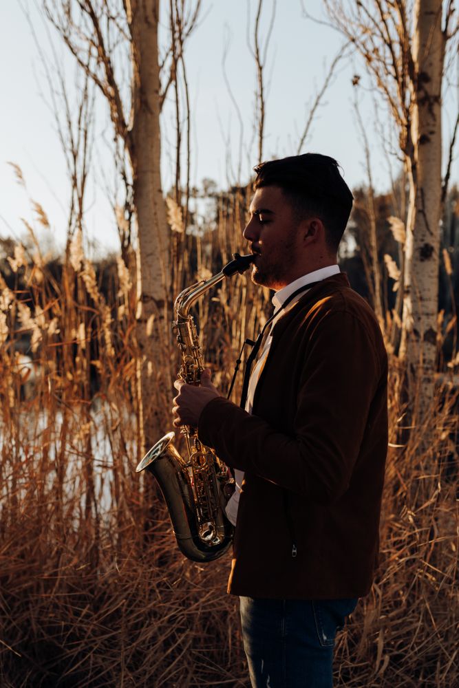 young musician playing the saxophone at sunset