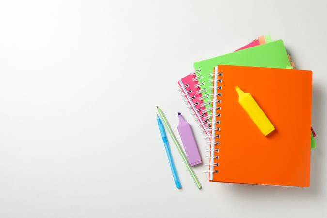 Top view of multi-colored notebooks and highlighters with space for text