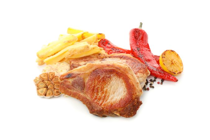 Fried pork steaks and vegetables isolated on light background. Grilled food