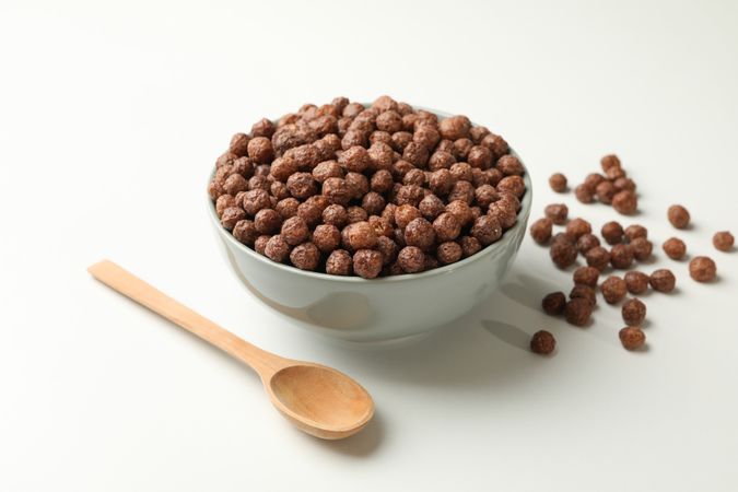 Spoon and bowl with corn balls on neutral background