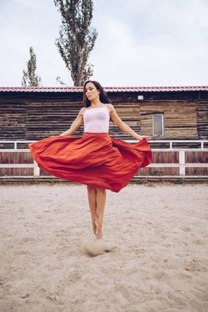 Woman in colorful skirt dancing at rural paddock